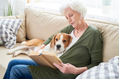 elderly woman reading with dog on lap