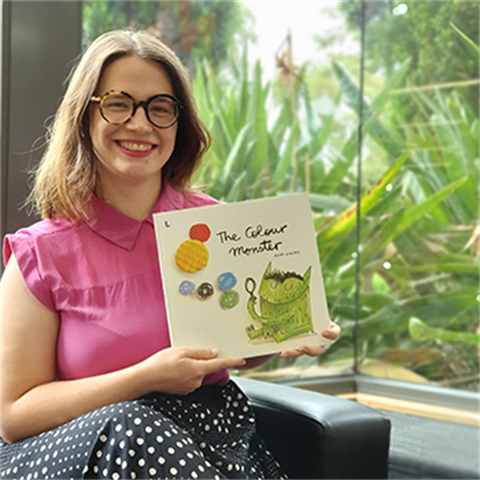 Youth librarian Emily holding a picture book