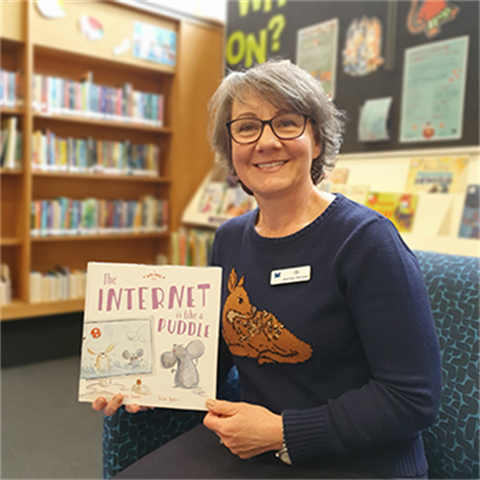 Youth librarian Lisa holding a picture book
