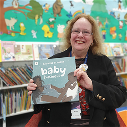 Youth librarian Michelle holding a picture book