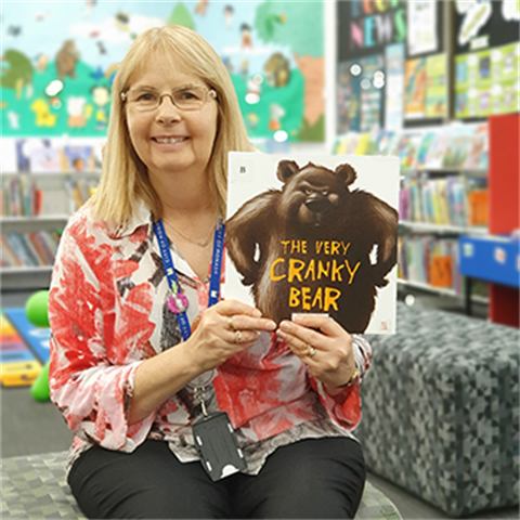 Youth librarian Suzi holding a picture book