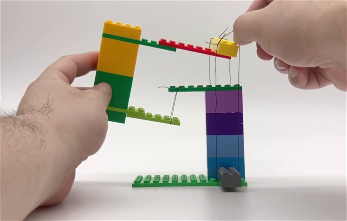 photo of hands building a Lego structure