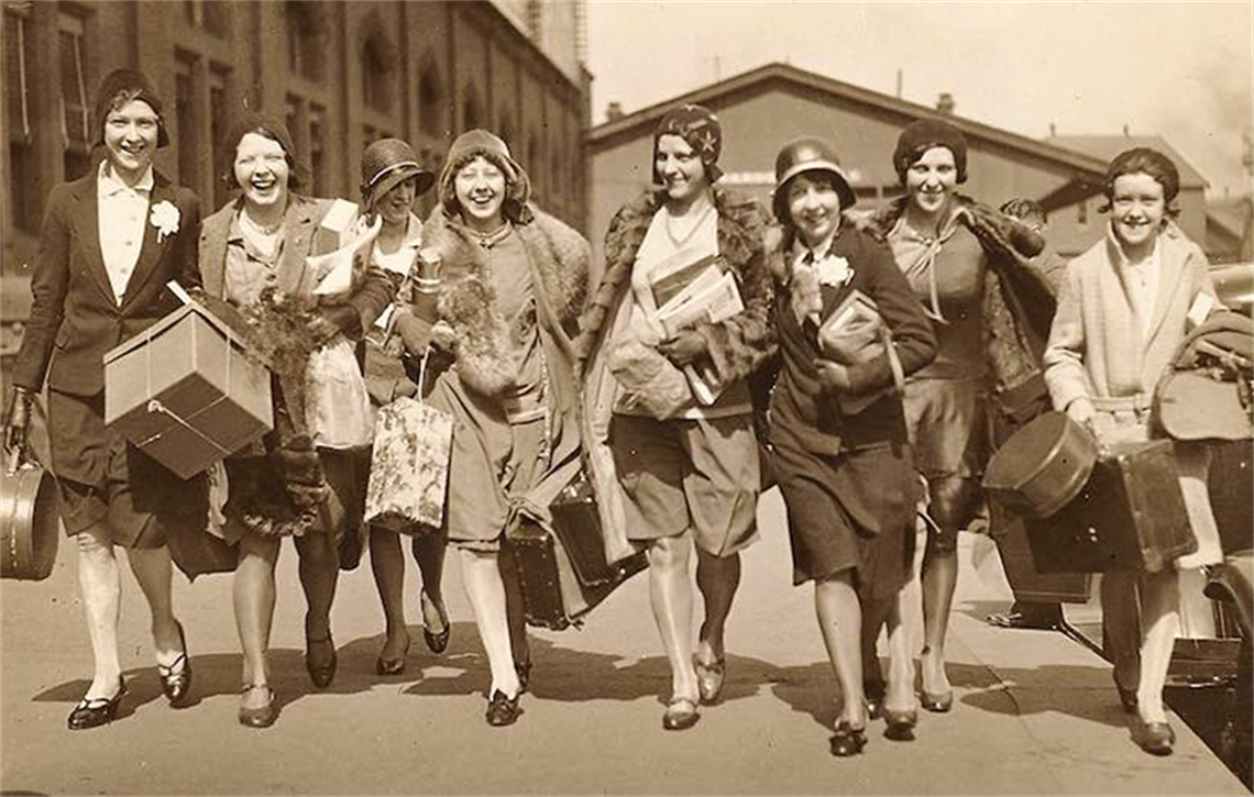 photo of women from the 1920s laughing with bags 