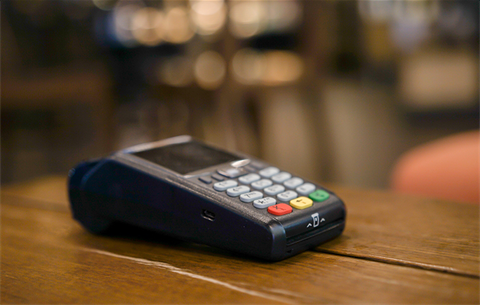 a photo of an EFTPOS terminal on a wooden desk