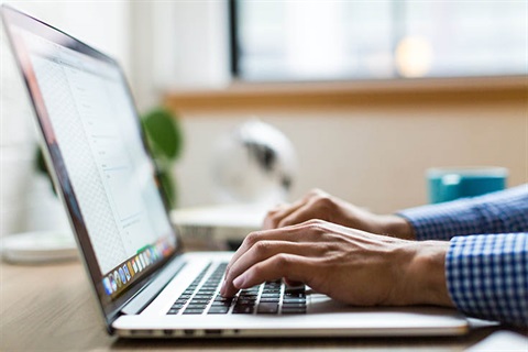 man typing on laptop