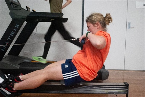 girl using rowing machine in low sensory room at ORC