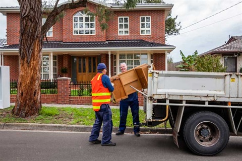 People putting items into a hard rubbish collection truck